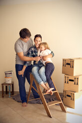 Happy family on step ladder beside cardboard boxes - TOYF001499