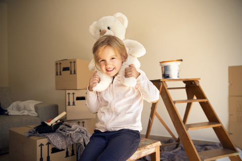 Girl with teddy bear and cardboard boxes in background stock photo