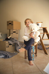 Mädchen mit Teddybär und Pappkartons im Hintergrund - TOYF001511