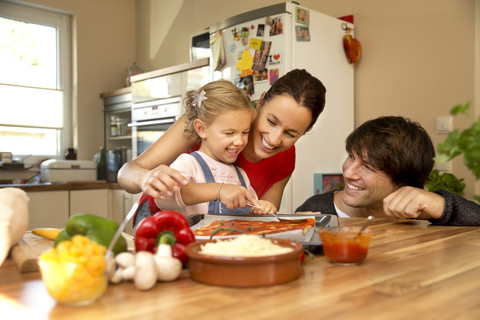 Glückliche Familie in der Küche bei der Zubereitung einer Pizza, lizenzfreies Stockfoto