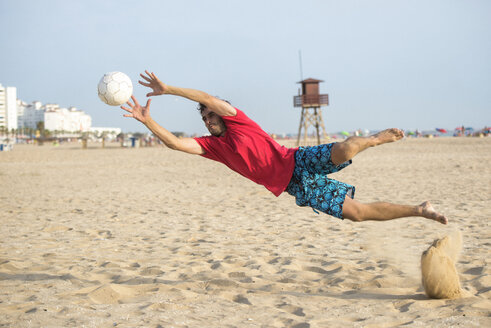 Spain, Cadiz, El Puerto de Santa Maria, Man playing soccer on the beach - KIJF000009