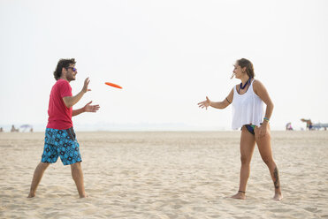 Spanien, Cadiz, El Puerto de Santa Maria, Pärchen spielt Frisbee am Strand - KIJF000011