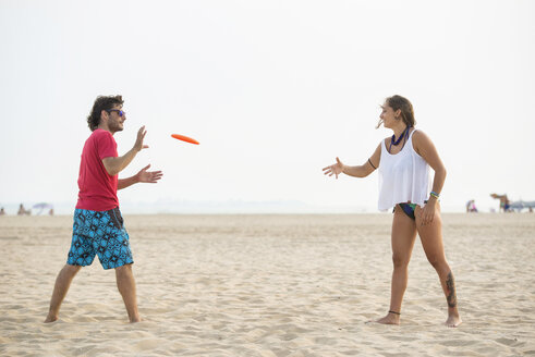 Spanien, Cadiz, El Puerto de Santa Maria, Pärchen spielt Frisbee am Strand - KIJF000011