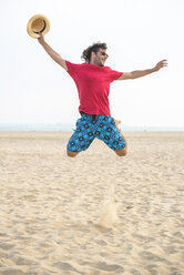 Spain, Cadiz, El Puerto de Santa Maria, Man jumping on the beach - KIJF000016