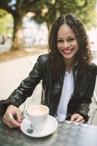 Porträt einer lächelnden jungen Frau mit einer Tasse Kaffee, lizenzfreies Stockfoto