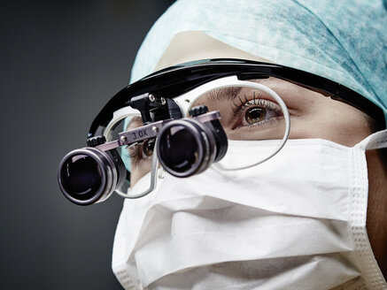 Portrait of young doctor wearing mask and magnifying spectacles - DISF002230
