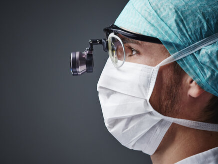 Young doctor wearing mask and magnifying spectacles - DISF002233