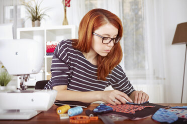 Portrait of young woman with sewing machine at home - SEGF000419