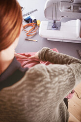 Rückenansicht einer jungen Frau mit Nähmaschine zu Hause - SEGF000422