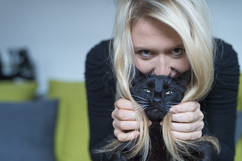 Porträt einer blonden Frau und ihrer schwarzen Katze, lizenzfreies Stockfoto
