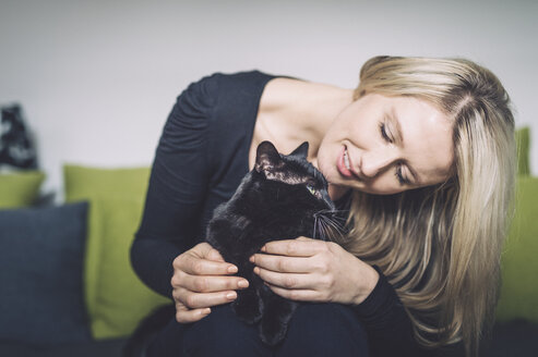 Blonde Frau und ihre schwarze Katze auf der Couch - FRF000360