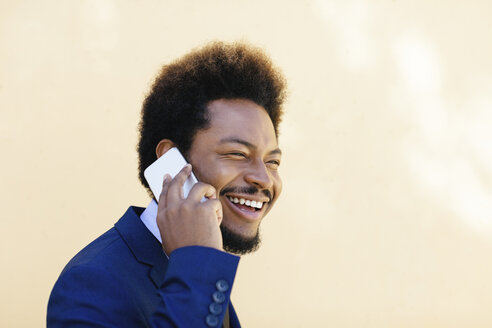 Porträt eines lächelnden jungen Geschäftsmannes, der mit einem Smartphone telefoniert - EBSF001010