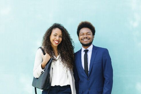 Porträt von zwei lächelnden jungen Geschäftsleuten vor einer blauen Wand - EBSF001013