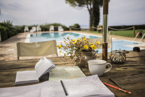 Italien, Toskana, Reiseführer, Karte und Notizbuch auf dem Tisch am Pool - RIB000384
