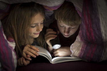 Bruder und Schwester lesen ein Buch unter einer Decke - SARF002302