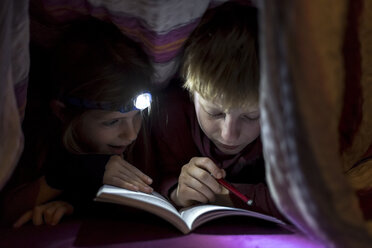 Bruder und Schwester lesen ein Buch unter einer Decke - SARF002303