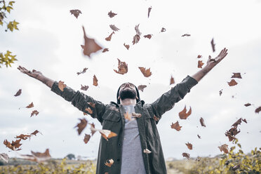 Young man throwing autumn leaves in the air - JRFF000182