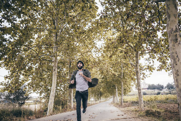 Spain, Tarragona, young man running on autumnal country road - JRFF000184