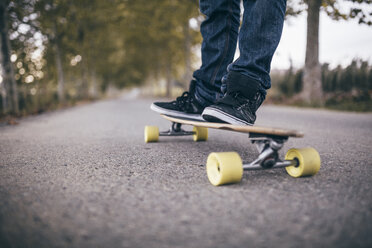 Man standing on longboard on a country road, close-up - JRFF000195