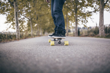 Man standing on longboard on a country road, partial view - JRFF000196