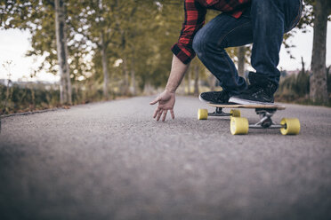 Man standing on longboard on a country road, partial view - JRFF000197