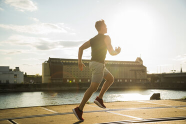 Young man running by the riverside - UUF005946