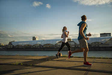 Young couple running by the riverside - UUF005953