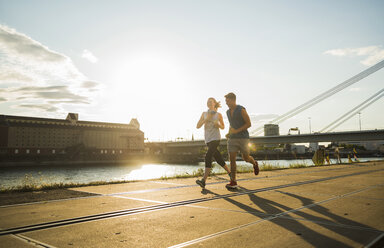 Young couple running by the riverside - UUF005954