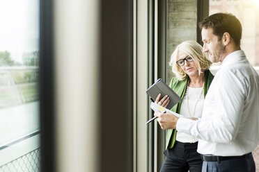 Portrait of smiling blond businesswoman communicating with a colleague - UUF005990