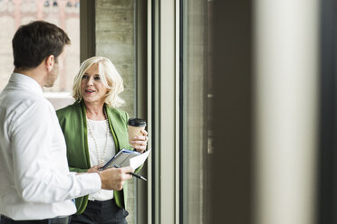 Portrait of smiling blond businesswoman communicating with a colleague - UUF005991