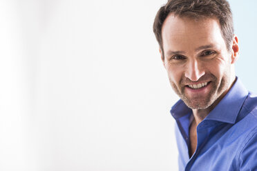 Portrait of smiling man with stubble wearing blue shirt - UUF006033