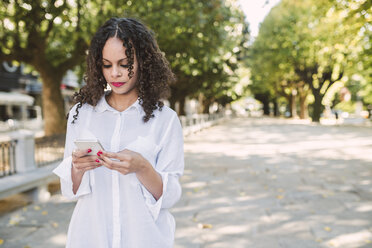 Porträt einer jungen Frau, die auf ihr Smartphone schaut - RAEF000637