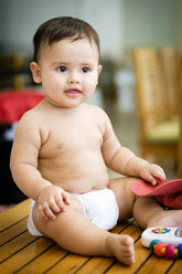 Portrait of baby boy sitting on a table in diapers - ABAF001947