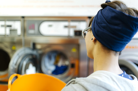 Rückenansicht einer jungen Frau in einem Waschsalon, lizenzfreies Stockfoto