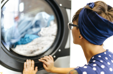 Junge Frau wartet in einem Waschsalon, lizenzfreies Stockfoto