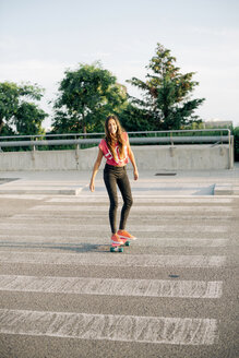 Porträt eines lächelnden Skateboarders auf einem Zebrastreifen - GEMF000471