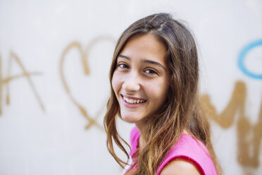 Portrait of happy girl in front of wall with graffiti - GEMF000478