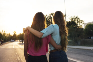 Back view of two female friends watching sunset arm in arm - GEMF000481