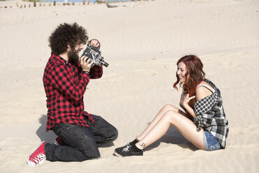 Spain, El Puerto de Santa Maria, young man filming his girlfriend on the beach - KIJF000024