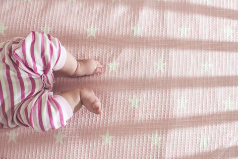 Baby girl lying in a cot, partial view stock photo