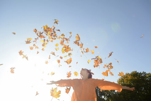 Young woman throwing autum leaves in the air - BFRF001637