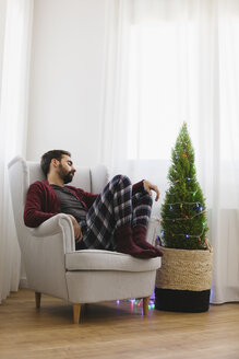 Mann schläft auf einem Sessel zu Hause zur Weihnachtszeit - EBSF001027