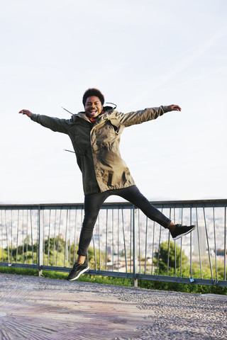 Spanien, Barcelona, Porträt eines fröhlichen jungen Mannes, der in die Luft springt, lizenzfreies Stockfoto