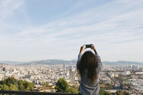 Spanien, Barcelona, Rückenansicht einer jungen Frau, die mit ihrem Smartphone ein Foto von der Aussicht macht - EBSF001078