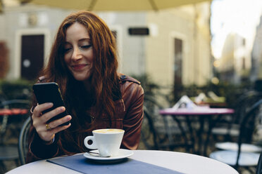 Frau mit Handy bei einem Kaffee im Freien in einer kleinen Bar - GIOF000480