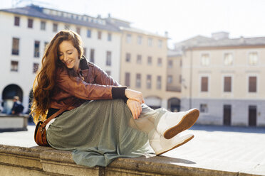 Italy, Padua, woman sitting outdoors at town square - GIOF000486