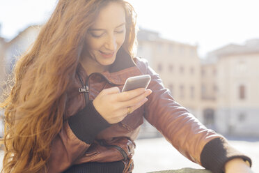 Italy, Padua, woman outdoors looking at cell phone - GIOF000492