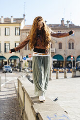 Italy, Padua, woman balancing on a wall - GIOF000493