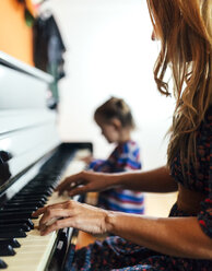 Woman and little girl playing piano together - MGOF001049