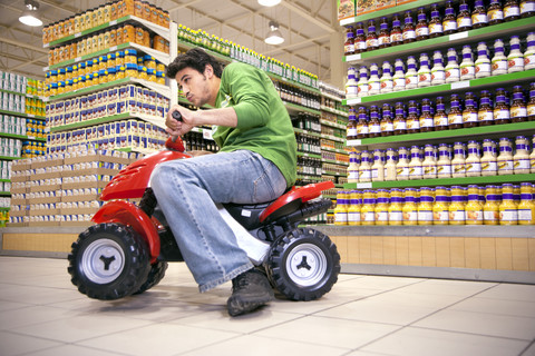 Man driving with toy car in a supermarket stock photo